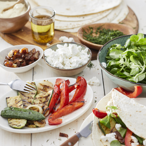 Wraps met hummus, gegrilde courgette, uien, paprika, geitenkaas & dadels